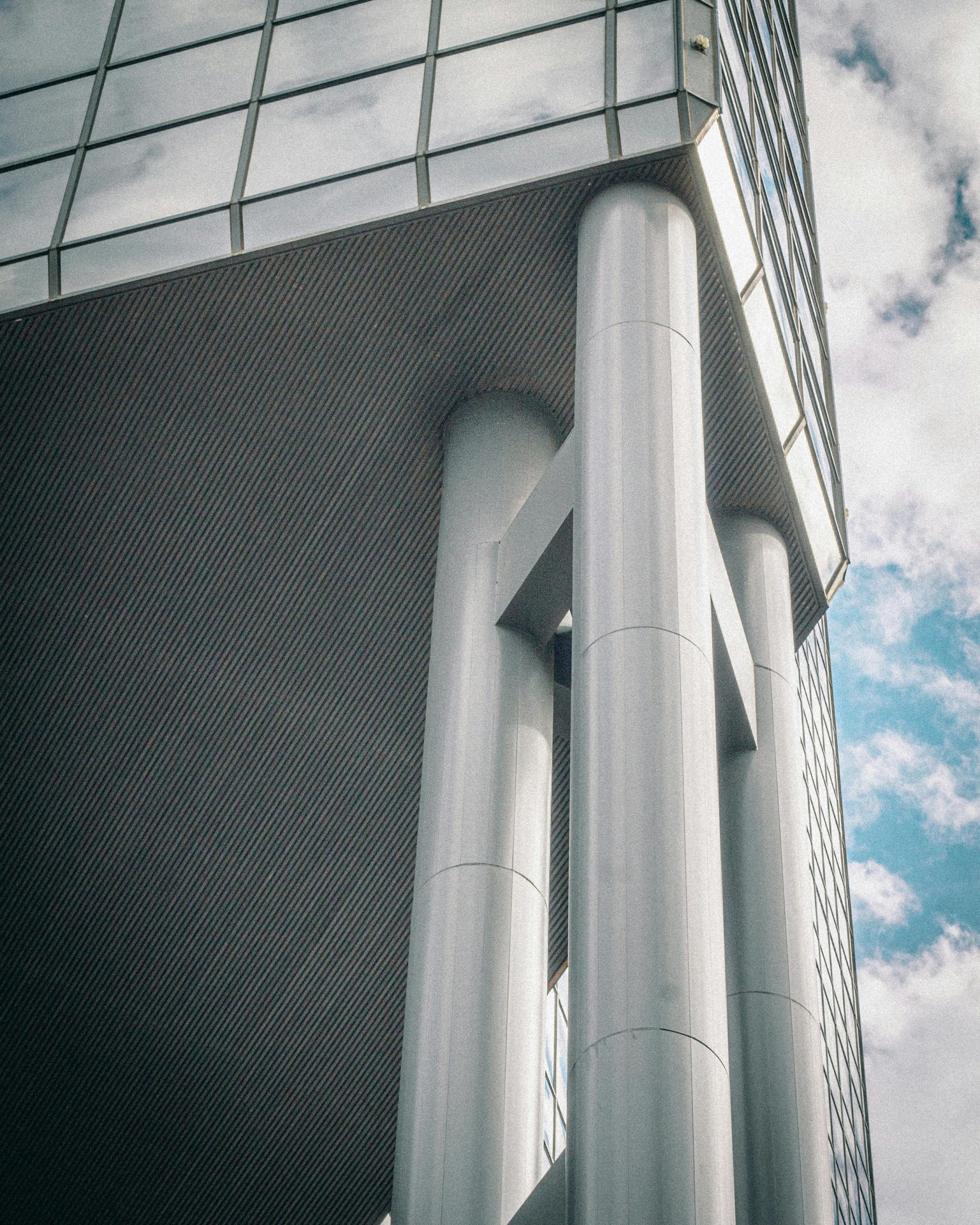 Close-up of a modern skyscraper's architectural pillars against a cloudy sky.