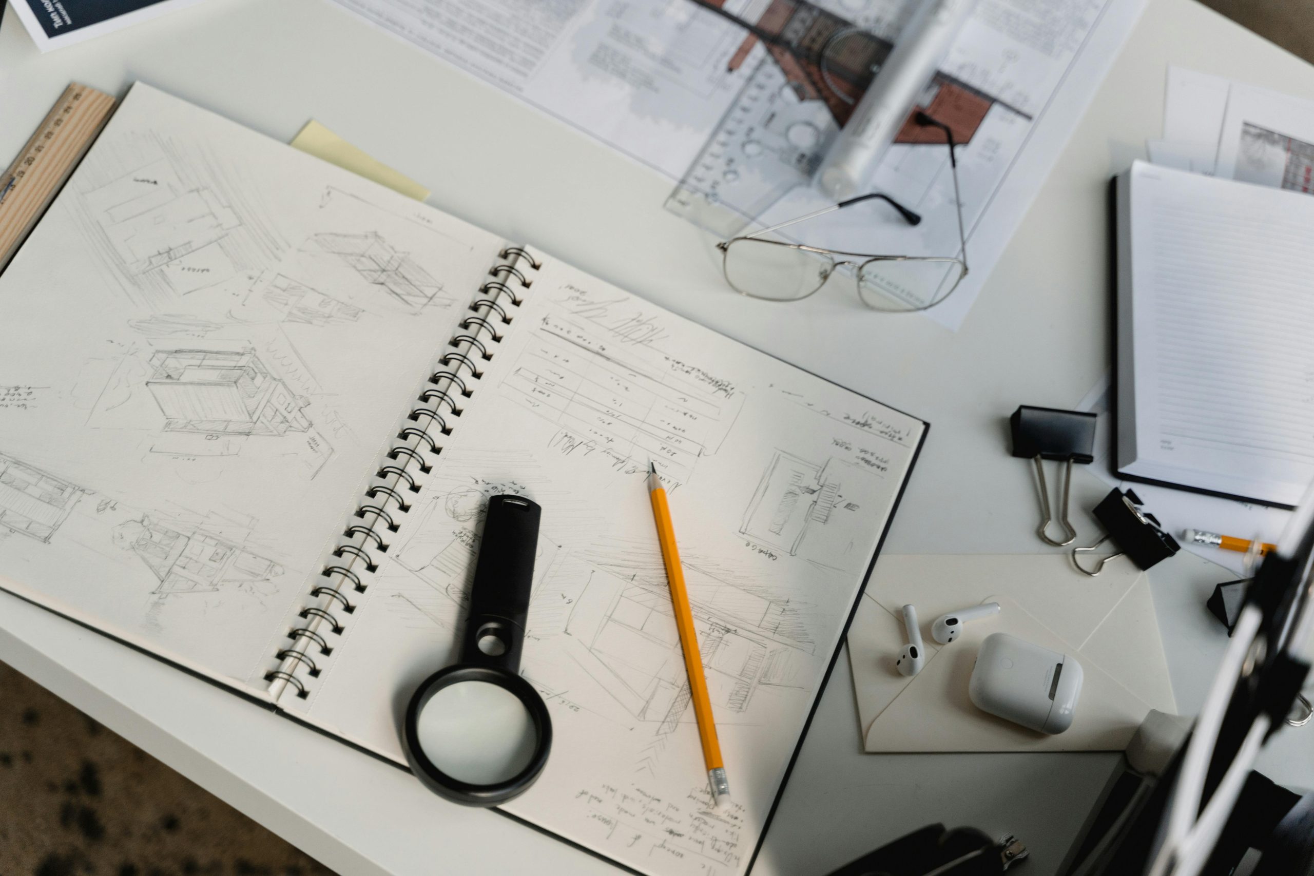 A high-angle view of a workspace with architectural sketches, tools, and office supplies, ideal for creative projects.